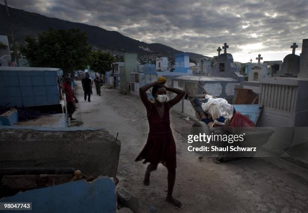 People walk by the body of a young man left on a wood crate in a cemetery on January 14, 2010 in Port au Prince, Haiti. Much of the country of Haiti...