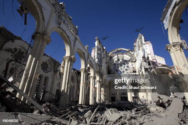 Helicopters fly over the heavily destroyed central Cathedral on January 15, 2010 in Port au Prince, Haiti. As the world rallies to help, emergency...