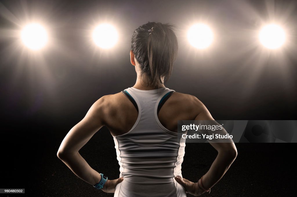 Rear view of female athlete wearing sports bra standing with hands