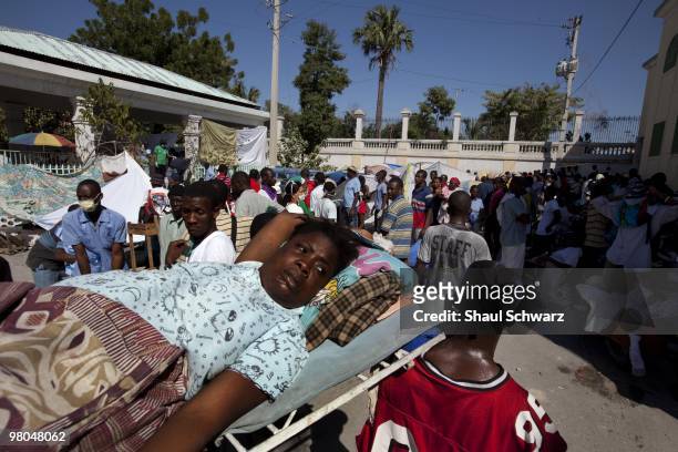 Man carries a woman to a make shift hospital in the streets of Downtown Port Au Prince following a massive 7.0 earthquake that has killed thousands....