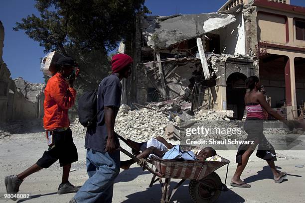 Man carries his boy to a make shift hospital on January 15, 2010 in Port au Prince, Haiti. As the world rallies to help, emergency efforts try and...
