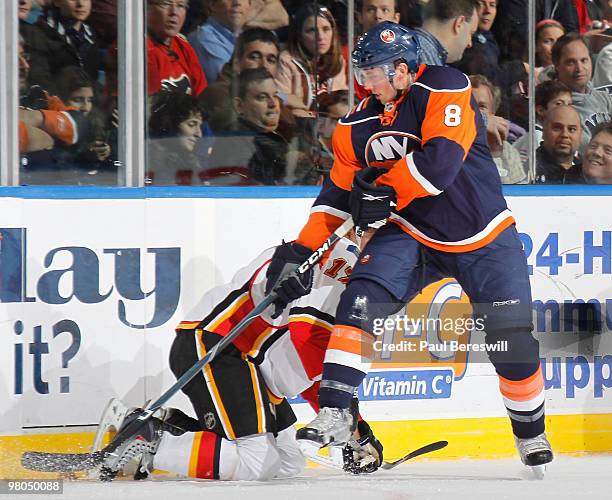 Rene Bourque of the Calgary Flames is knocked to the ice as Bruno Gervais of the New York Islanders takes the puck in the second period of an NHL...