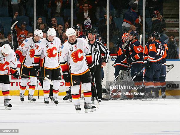 Goaltender Martin Biron of the New York Islanders celebrates a win with teammates John Tavares and Richard Park as the Calgary Flames skate off the...