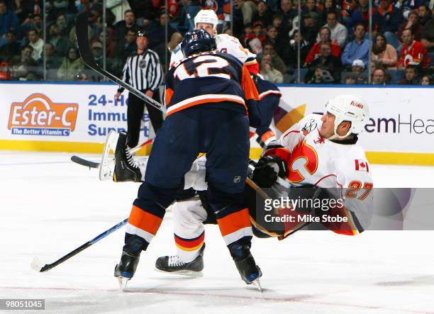 Steve Staios of the Calgary Flames is knocked to the ice by Josh Bailey of the New York Islanders on March 25, 2010 at Nassau Coliseum in Uniondale,...