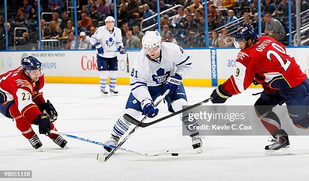 Phil Kessel of the Toronto Maple Leafs pushes the puck between Jim Slater and Johnny Oduya of the Atlanta Thrashers at Philips Arena on March 25,...