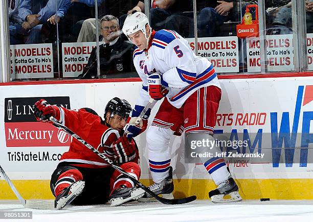 Dan Girardi of the New York Rangers fights for the puck with Dainius Zubrus of the New Jersey Devils at the Prudential Center on March 25, 2010 in...