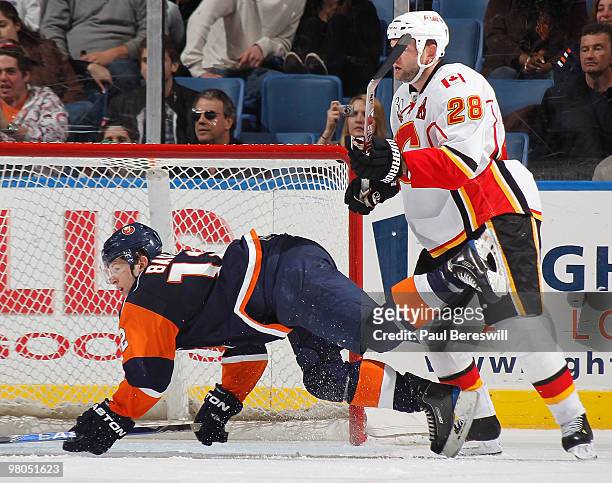 Robyn Regehr of the Calgary Flames knocks over Josh Bailey of the New York Islanders in front of the Calgary net during the third period of an NHL...