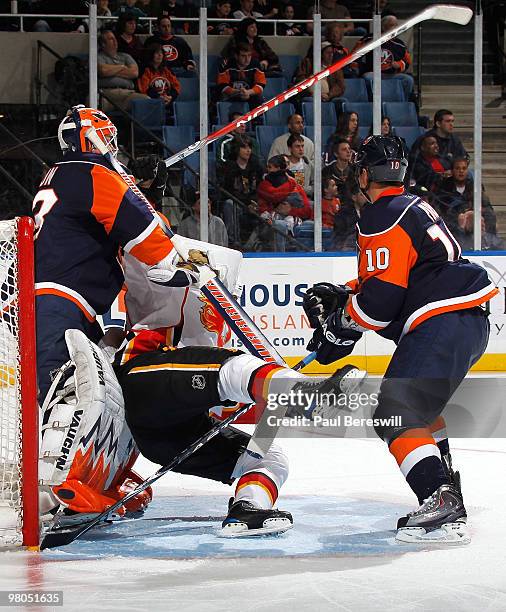 Eric Nystrom of the Calgary Flames is sent flying along with his stick by Richard Park and goalie Martin Biron of the New York Islanders in the third...