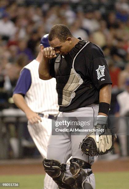 Florida Marlins catcher Miguel Olivo rubs his eye eye after a bat splintered during play against the Arizona Diamondbacks at Chase Field in Phoenix,...