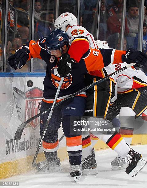 Steve Staios of the Calgary Flames ties up Bruno Gervais of the New York Islanders as they battle for the puck in the second period of an NHL game at...