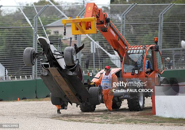 Track marshalls carry the Sauber car of Japanese driver Kamui Kobayashi off the circuit after he crashed during the first practice session to Formula...