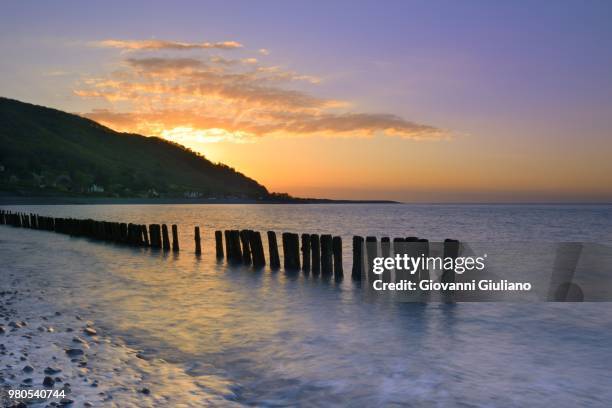 seascape with wooden poles at sunset, devon, england, uk - porlock stock-fotos und bilder