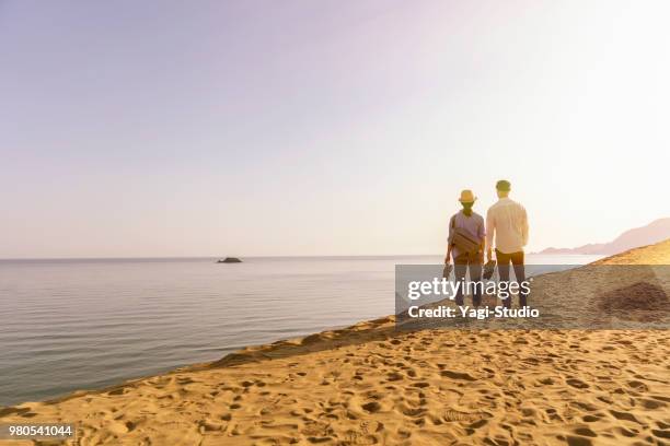 paar reisende zu fuß in einer sanddüne mit blick auf das meer - couple dunes stock-fotos und bilder