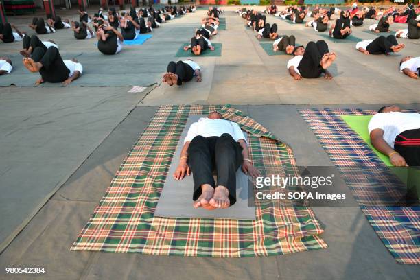 Members of the military force raising their feet while laying on the ground during the yoga session. Soldiers of paramilitary force doing yoga on the...