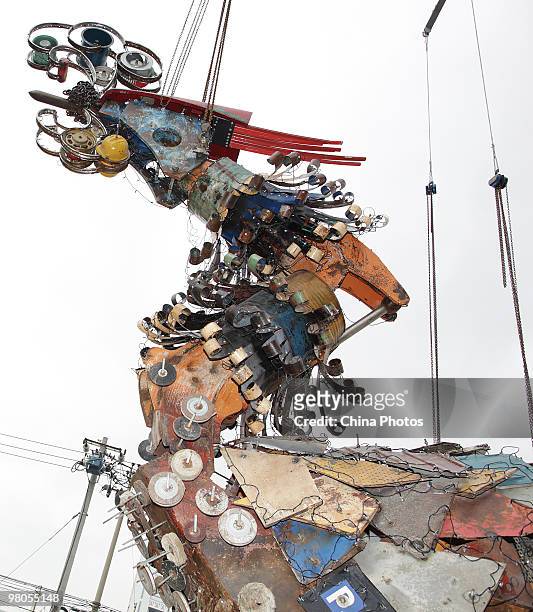 Phoenixe, one of Xu Bing's towering sculptural masterpiece 'The Phoenixes', is lifted at the square of Today Art Museum on the preparation for its...