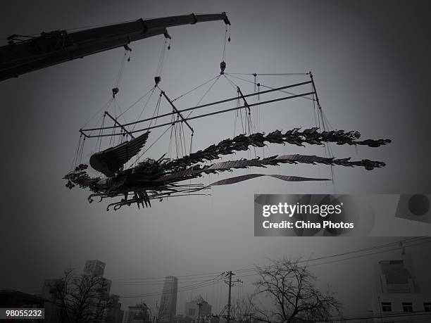 Phoenixe, one of Xu Bing's towering sculptural masterpiece 'The Phoenixes', is lifted at the square of Today Art Museum on the preparation for its...