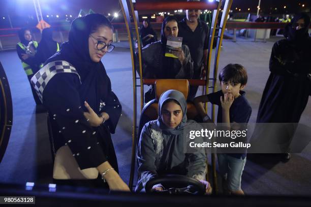 Sondos Ashi tries out a car driving simulator as members of her family look on during an outdoor educational driving event for women on June 21, 2018...