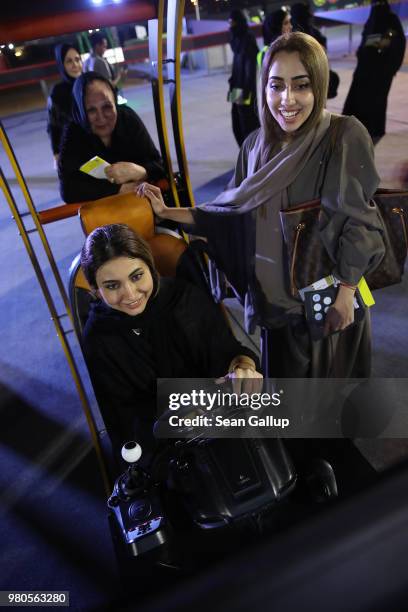 Sara Sulaiman tries out a car driving simulator as her sister Areej Al-Rashdi and her mother look on during an outdoor educational driving event for...