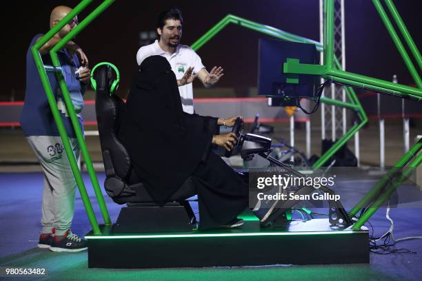 Woman who is wearing a traditional Muslim niqab tries out a car driving simulator during an outdoor educational driving event for women on June 21,...