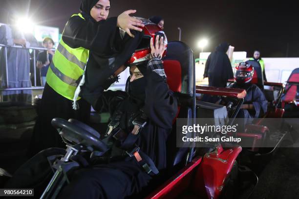 Young woman who is wearing a traditional Muslim niqab gets help puting on a helmet as she prepares to drive a go-kart at an outdoor educational...