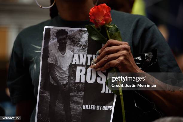 Woman holds a rose and a sign for Antwon Rose as she joins more than 200 people gathered for a rally to protest the fatal shooting of Rose at the...