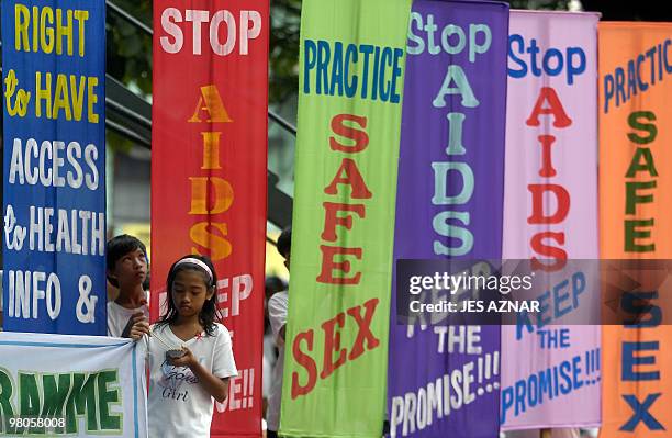 Children stands next to banners displayed during a march to mark World Aids Day in Olongapo city, Zambales, northern Philippines on December 1, 2008....