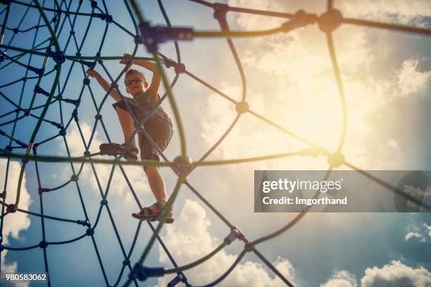 kleine jongen spelen op de speelplaats klimmen web - touw stockfoto's en -beelden