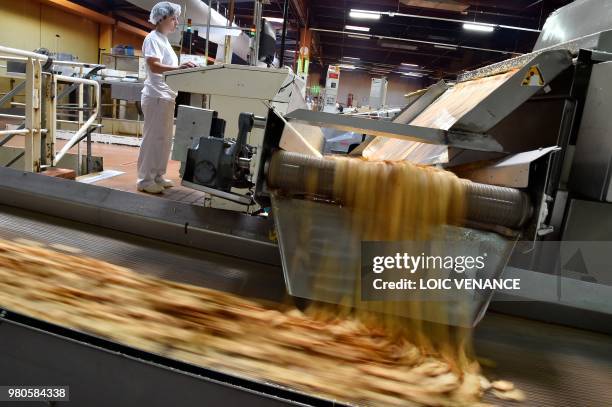 An employee works on the production line of the "Petit Beurre" biscuits at the French biscuit manufacturer LU in La Haye-Fouassiere, near Nantes,...