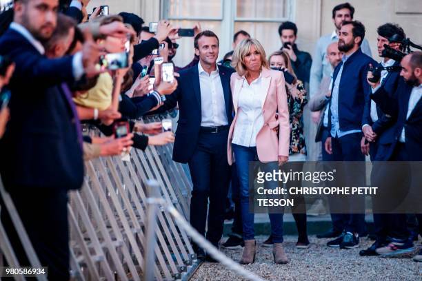 French president Emmanuel Macron and his wife Brigitte Macron listen to music next to people during the annual "Fete de la Musique" in the courtyard...