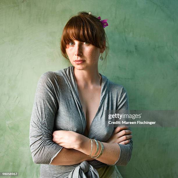girl in front of green wall with her arms crossed - mareen fischinger foto e immagini stock