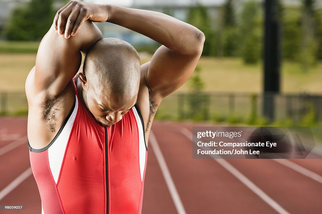 Man stretching his muscles beside a running track