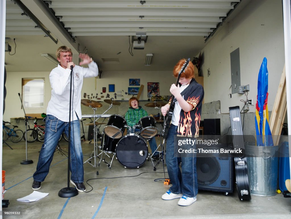Three male teenagers playing music in garage