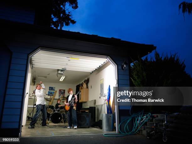 teen garage band practicing at night in garage  - gruppo musicale foto e immagini stock