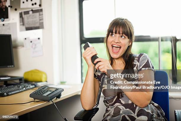 woman speaking loudly into a telephone - bang palabra en inglés fotografías e imágenes de stock