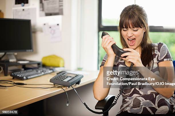 woman yelling into telephone headset - hate palabra en inglés fotografías e imágenes de stock