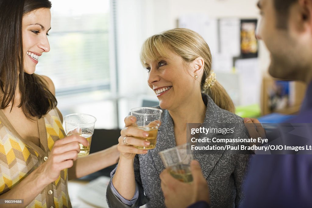 Three business people holding drinks