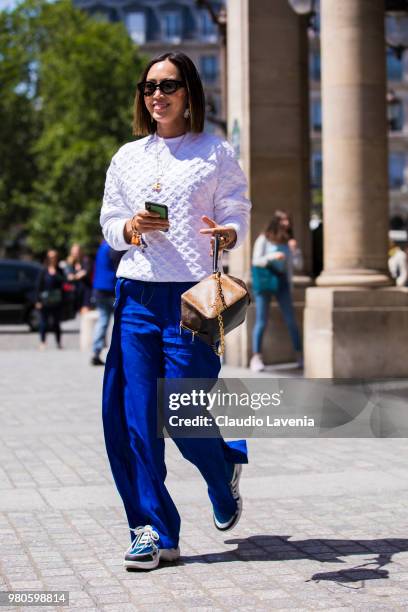 Aimee Song, wearing white sweaters and blue pants, is seen in the streets of Paris before the Louis Vuitton show, during Paris Men's Fashion Week...