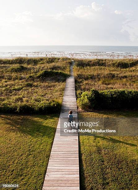 boy running on path to beach - the charleston stock pictures, royalty-free photos & images