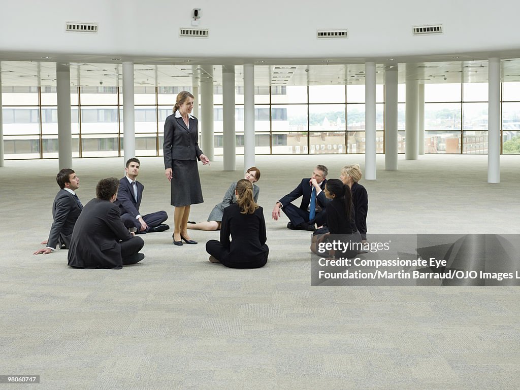 Business people sitting around business woman