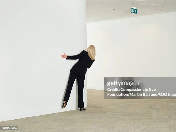 a woman peering around a corner - spähen stock-fotos und bilder