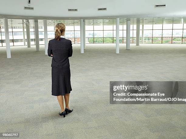 business woman standing in large empty room - commercial real estate agent stock pictures, royalty-free photos & images