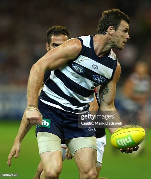 Cameron Mooney of the Cats handballs during the round one AFL match between the Geelong Cats and the Essendon Bombers at Melbourne Cricket Ground on...