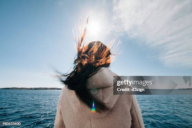 rear view of woman standing on boat enjoying sea breeze and admiring ocean - blowing hair stock pictures, royalty-free photos & images