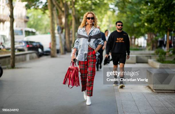 Elina Halimi wearing red Balenciaga bag with fringes, red lumberjack pants, button shirt with newspaper print is seen outside Issey Miyake on day...