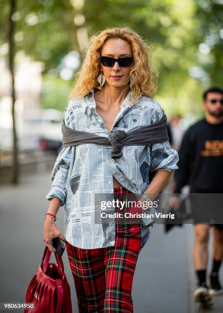 Elina Halimi wearing red Balenciaga bag with fringes, red lumberjack pants, button shirt with newspaper print is seen outside Issey Miyake on day...