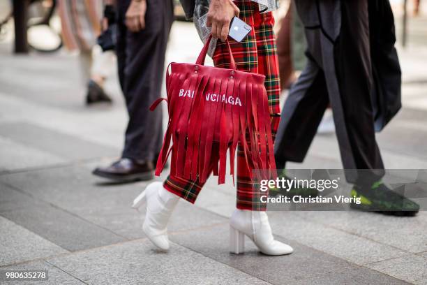 Elina Halimi wearing red Balenciaga bag with fringes, red lumberjack pants, button shirt with newspaper print is seen outside Issey Miyake on day...