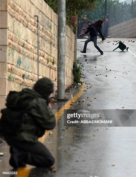 Palestinian protesters hurl stones at an Israeli soldier during clashes in the West Bank village of Nabi Saleh near Ramallah following a protest...