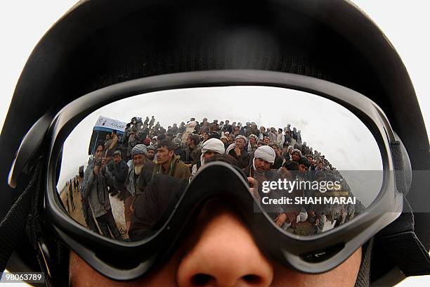 Spectators watching a game of buzkashi, a traditional sport played on horseback, are seen reflected in the goggles of an Afghan police official in...