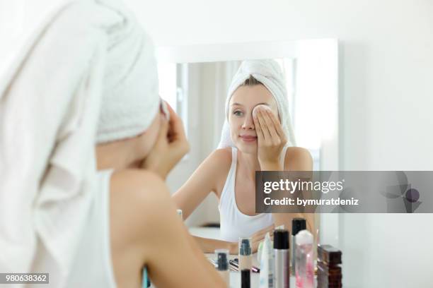 jolie jeune femme nettoie son visage - démaquillant photos et images de collection