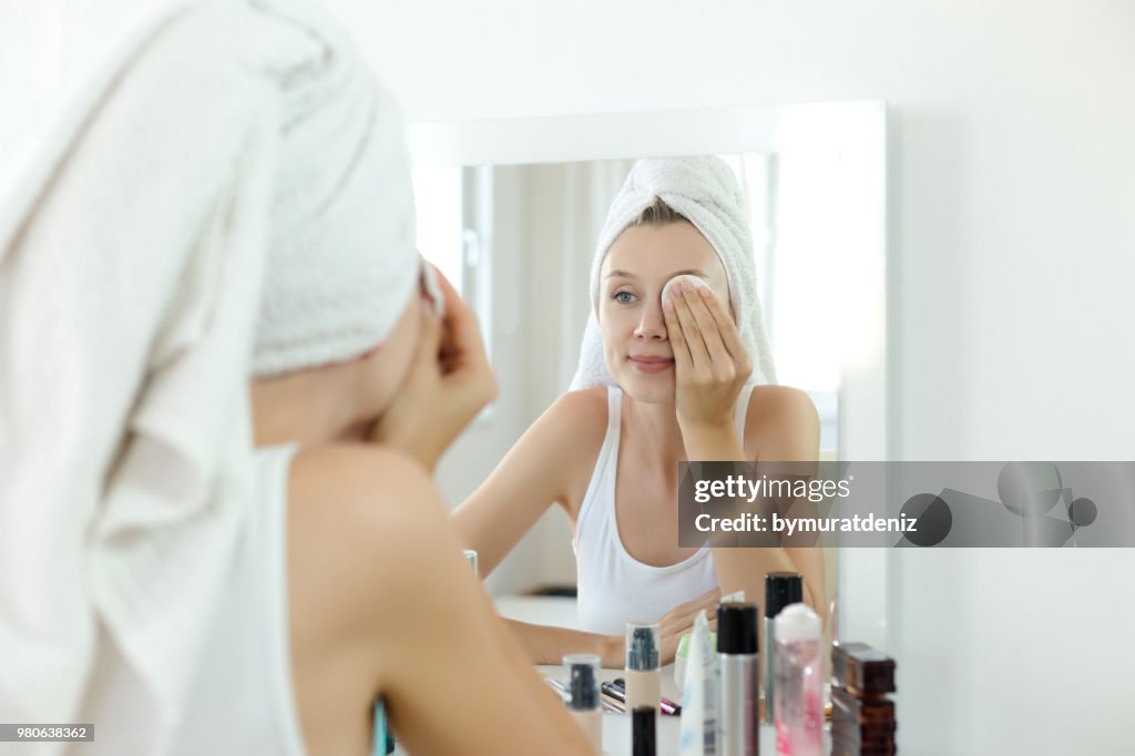 Pretty young woman is cleaning her face